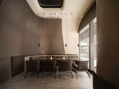 Modern restaurant interior featuring concrete walls and wooden furniture.