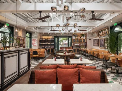 Interior of a cafe bar with wooden furniture, concrete flooring, and indoor plants.