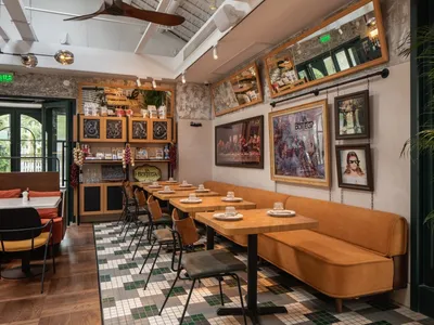 Industrial-style restaurant interior with wooden tables, metal chairs, and tiled floor.