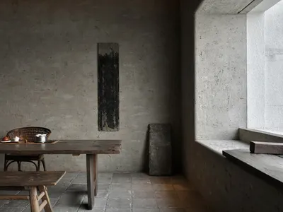 簡約風格的廚房內有木製餐桌、混凝土牆面，以及從窗戶灑落的自然光線。
