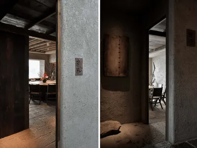 A modern restaurant interior featuring a concrete wall and wooden beams.