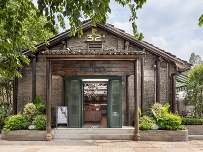 A rustic restaurant with a brick exterior and tile roof surrounded by lush greenery, featuring the number 32 and the name 'La