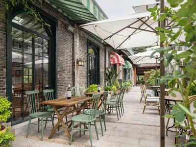 A cozy outdoor seating area with wooden furniture and greenery in a cafe setting
