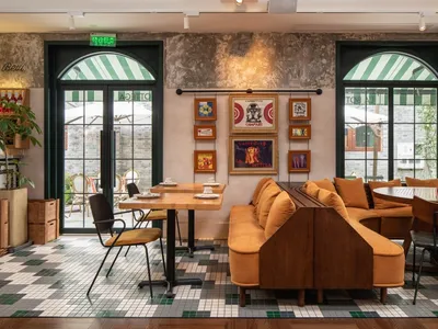 Industrial-style restaurant interior with rustic wooden furniture, mismatched table settings, and vintage decor