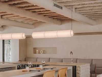 Modern restaurant interior with concrete counter bar, wooden chairs, and white pendant lights.