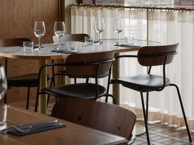 An industrial-style restaurant interior featuring marble countertops and wooden chairs.