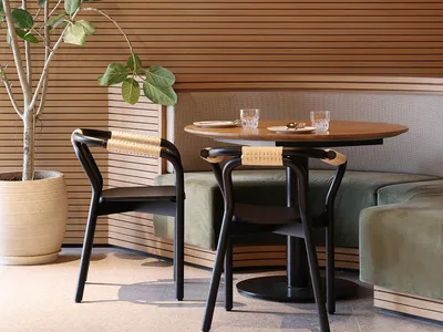Industrial-style restaurant interior with wooden walls and furniture, green plant, round wooden table, and hanging modern lig