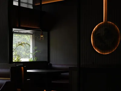 A modern restaurant interior featuring dark tones and illuminated elements.