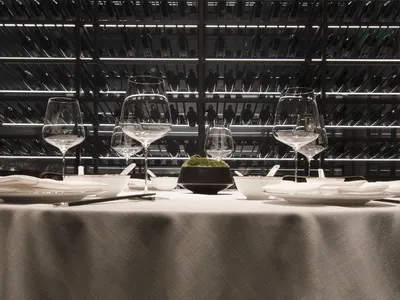 A modern industrial restaurant interior with metal racks, glassware, and minimalist design.