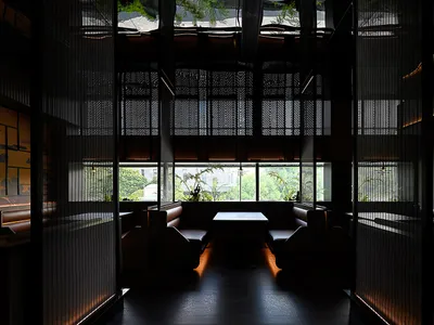A modern restaurant interior featuring comfortable leather seating and glass paneling.