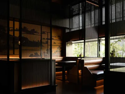 現代工業風餐廳室內，深色牆面搭配金屬欄杆，窗邊自然光營造溫暖氛圍。