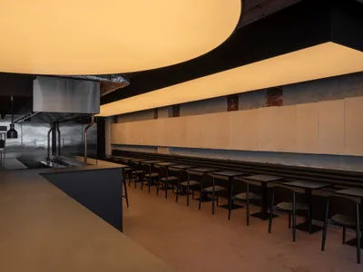 Industrial-style restaurant interior with metal counters and seating.