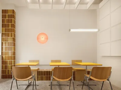 Modern café interior with wooden tables, chairs, and terrazzo tile wall