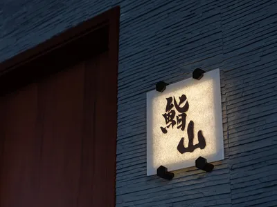A modern restaurant signage with paper lightbox illumination displaying black characters against a wooden background.