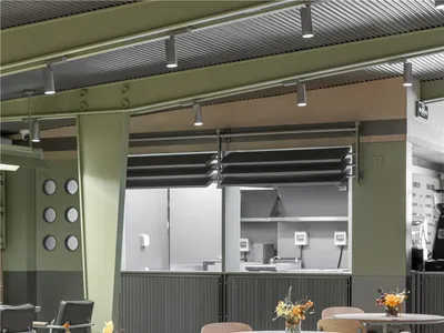 Modern cafe interior with wooden tables, metal chairs, and minimalistic design.