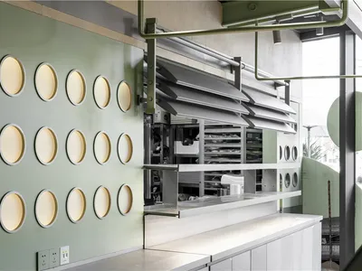 The interior of a modern restaurant featuring a wall with circular glass panels.