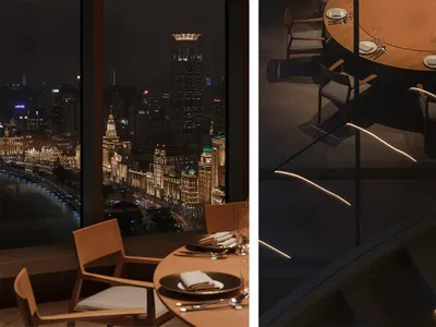 Modern restaurant dining area with a view of the cityscape at night, featuring wooden tables, chairs, and place settings.