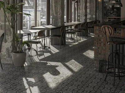 Industrial restaurant with concrete, brick, and metal elements, featuring seating areas and a bar.