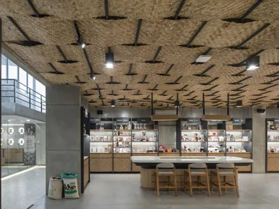 Interior design of a coffee shop featuring a bamboo ceiling and concrete columns with a display of coffee-related products an