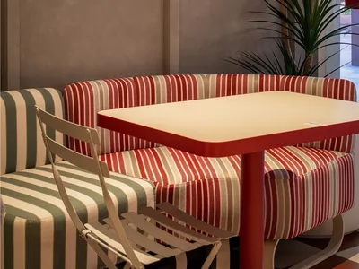 A cozy cafe setting featuring a striped sofa with a white table and a sleek wall-mounted light fixture.