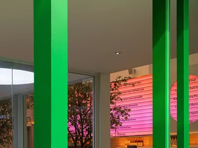 餐廳室內設有綠色柱體、玻璃牆面，以及粉紅色菜單板。