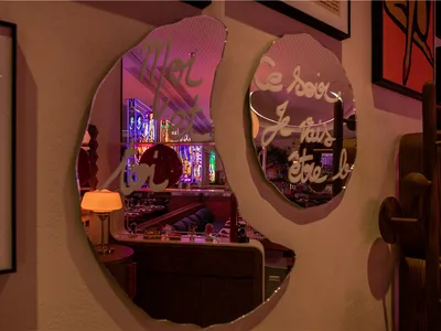 A modern restaurant interior with metallic wall art and stained glass windows.