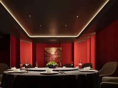 A luxurious private dining room with red leather seating and a circular dining table.