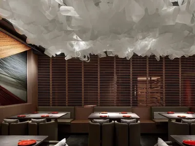 A modern restaurant interior featuring a white fabric ceiling, wooden slatted walls, and sleek seating.