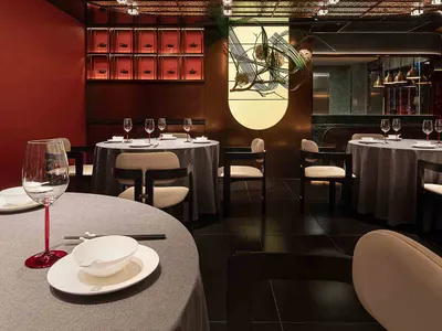 A modern restaurant interior with metallic ceiling, round tables, and chairs.