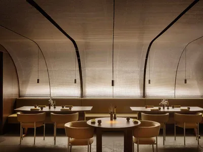 A modern restaurant interior featuring neutral-tones seating and tables adorned with minimalist decor.