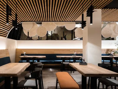 Modern restaurant interior with wooden tables and chairs, featuring a contemporary design with a mix of wood and metal materi