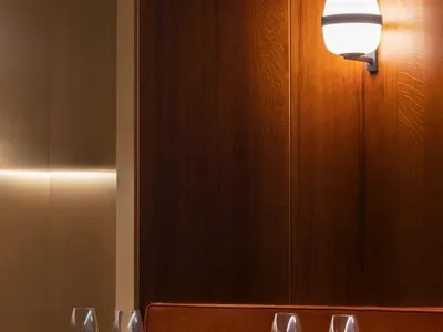 A modern restaurant interior featuring wooden walls, leather seating, and glassware.