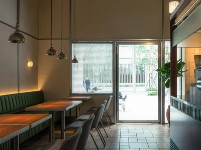 A modern cafe interior featuring wooden tables, metal chairs, and glass elements.