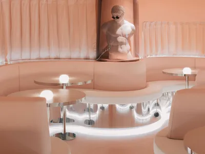 A modern bar interior with pink leather seating and stainless-steel tables.