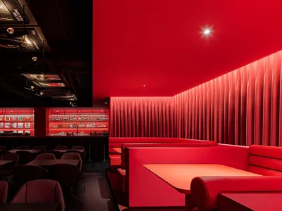 A modern restaurant bar with red curtains and a bright, cozy atmosphere.
