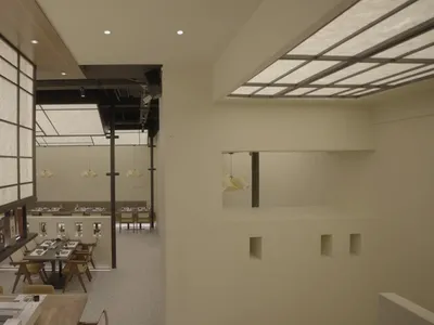 A modern restaurant interior with minimalist design, showcasing sleek white walls and lighting.