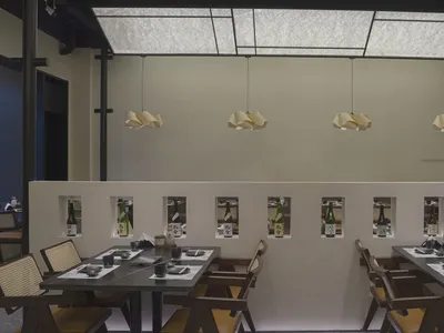 Minimalist design featuring wooden tables, concrete walls, and glass windows in a modern restaurant setting.