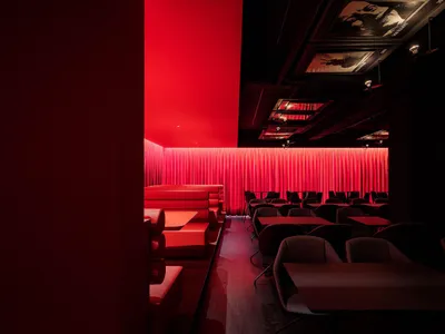 A modern restaurant with red curtains and tables.