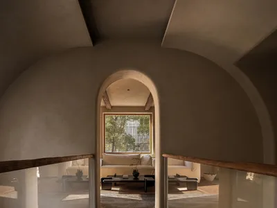 A modern living room with concrete arches, featuring a comfortable sofa and a coffee table, set against a backdrop of natural