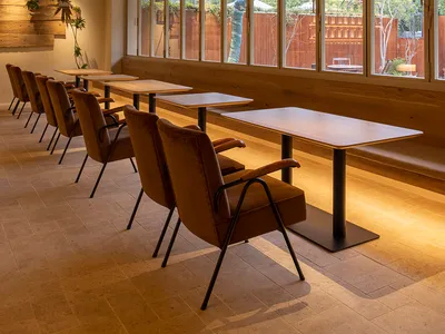 Modern restaurant interior with tables, chairs, and large windows.