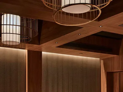 A sleek modern restaurant bar with wooden paneled walls and a counter made of natural wood.