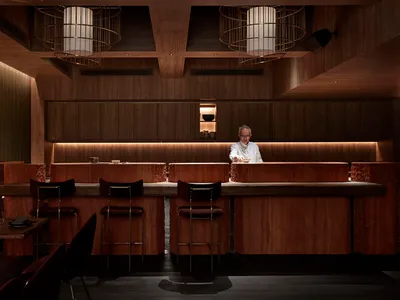 Modern restaurant bar with wooden counter and seating.