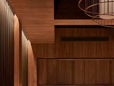 Modern restaurant with wooden bars and seating, featuring warm lighting and contemporary design.