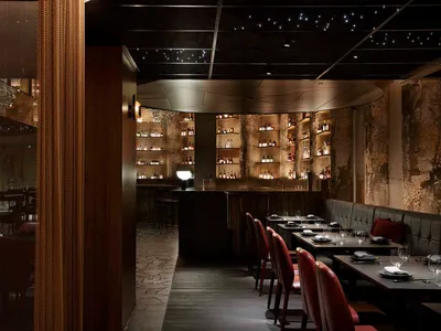 Interior design image of a modern restaurant featuring a textured concrete wall and brown leather seating