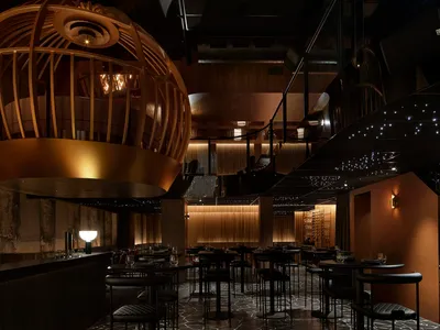 A modern restaurant interior featuring metallic structures and leather seating.