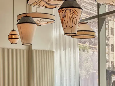 Sunny cafe interior with modern textile lighting and wooden furniture.