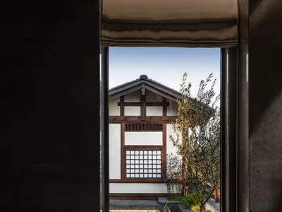 Modern restaurant with concrete floor, minimalist design, and a view of a traditional building through a window.