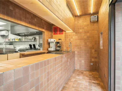 A cafe interior featuring a countertop with terracotta tiles and a professional kitchen setup.