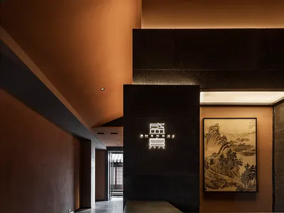A contemporary hotel reception area with concrete walls and an illuminated logo.