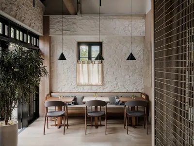 Modern restaurant interior with white walls, wooden tables, and dark pendant lights.